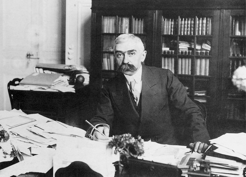 05-Pierre-de-Coubertin-at-the-age-of-40-sitting-behind-his-desks-Navacelle-Collection-1488x1068px